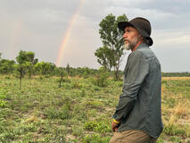Dr. Steve Boyes with a rainbow in the background experiences the first signs of the rainy season